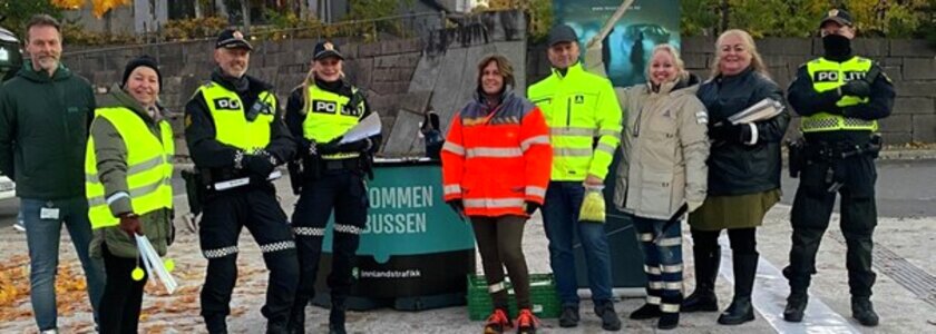 Bilde av flere personer fra politiet og Trygg Trafikk og flere som står på stand på Lillehammer skysstasjon og deler ut refleks til reisende - Klikk for stort bilde