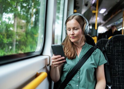 Dame sitter på bussen og ser på telefonen - Klikk for stort bilde